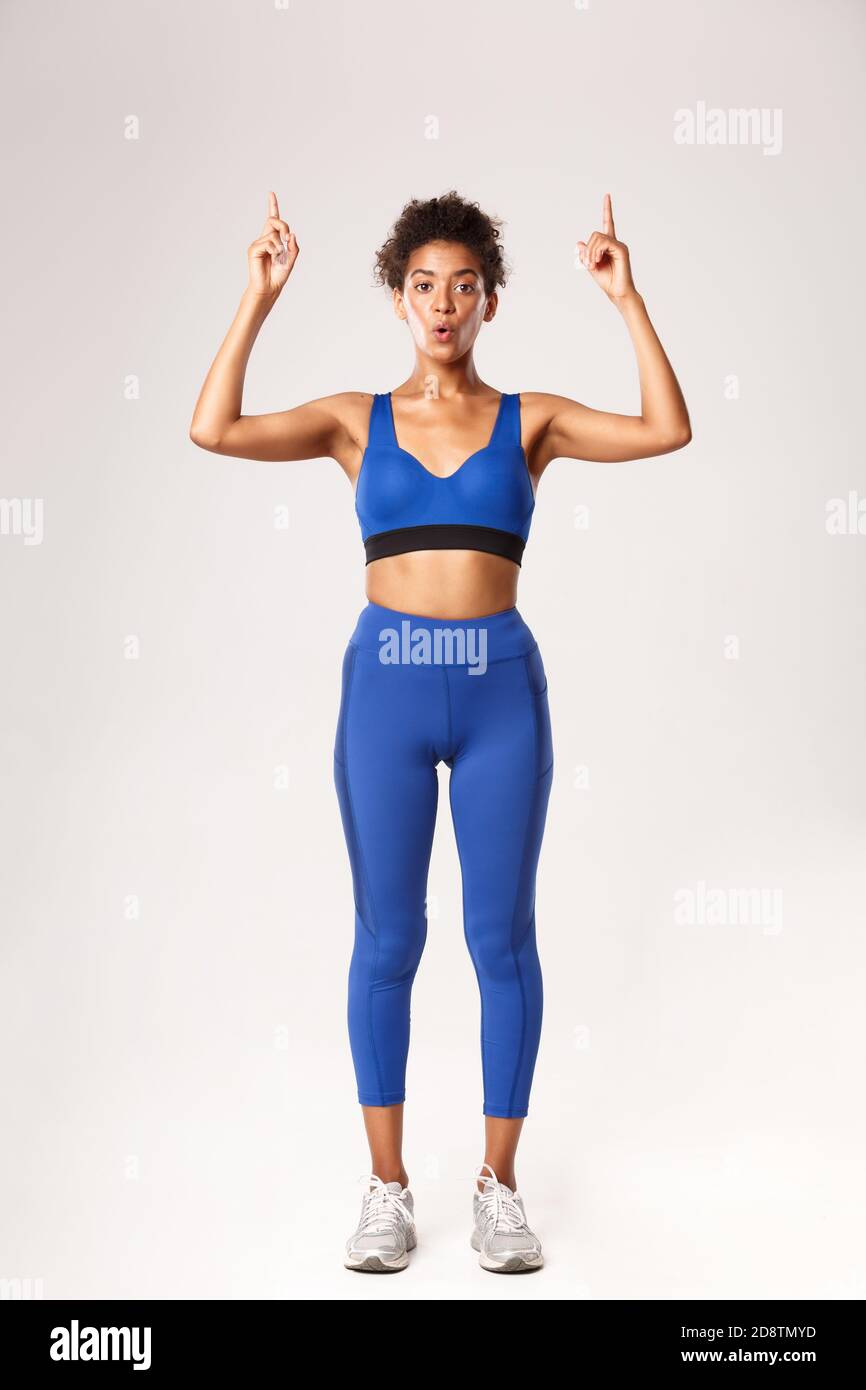 Full length of amazed good-looking fitness girl in blue sports bra and  leggings, pointing fingers up, showing promo about workout or gym, standing  Stock Photo - Alamy