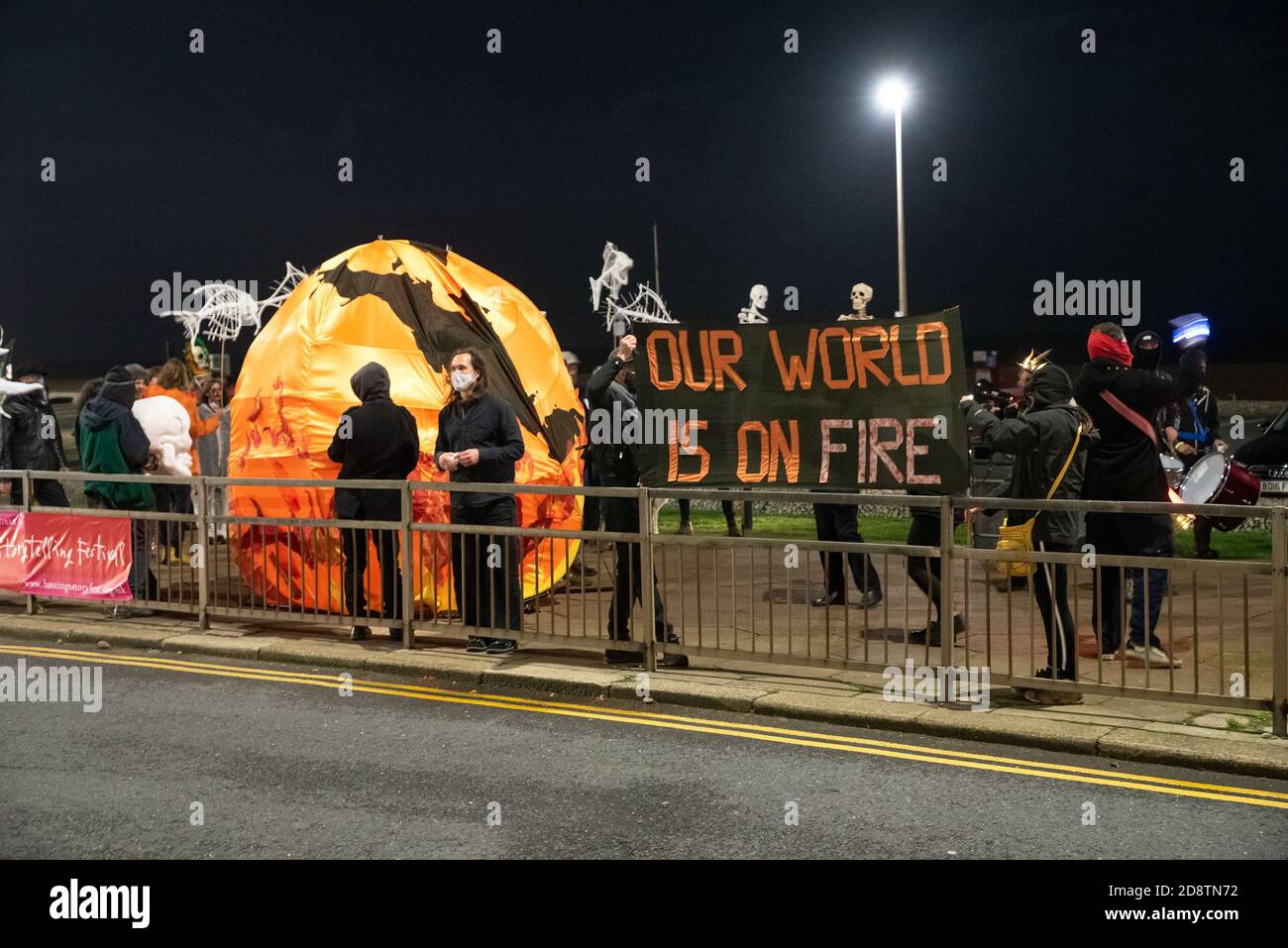 Hastings, UK. 31st October 2020. Extinction Rebellion Halloween Protest and March. The lively march left the Old Town once dark, and included loud samba drummers, skeletons, brightly lit bicycles, a world on fire effigy, fire torches and ended with smoke bombs. Roads were blocked by 10M banners to allow the march to safely cross roads. The protest demanded immediate and meaningful action from the Government to meet the challenges of a Climate Emergency. Hosted by Extinction Rebellion Hastings / St Leonards and Extinction Rebellion Southeast UK. Credit: Stephen Bell/Alamy Stock Photo