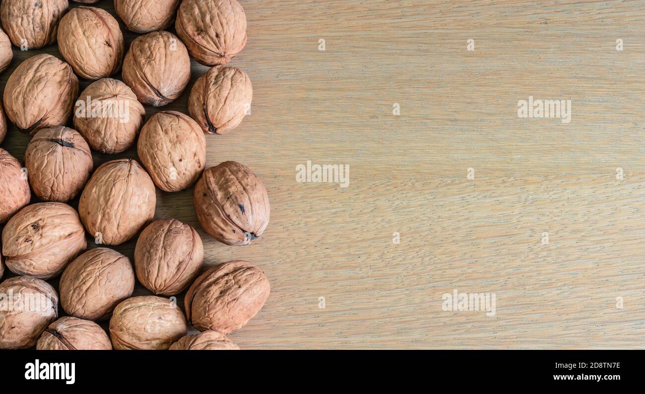 Border of whole walnuts on wooden background. Stock Photo