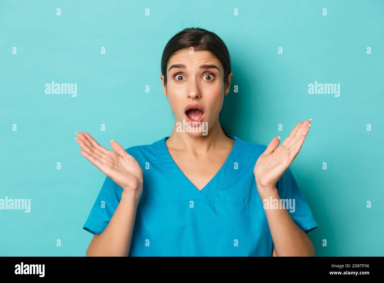 Coronavirus, social distancing and health concept. Close-up of alarmed and anxious female doctor, spread hands sideways and drop jaw, looking worried Stock Photo