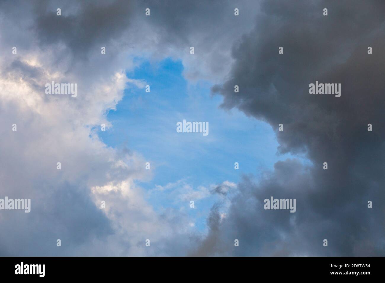 natural blue sky window in clouds, round gap in solid summer clouds Stock Photo