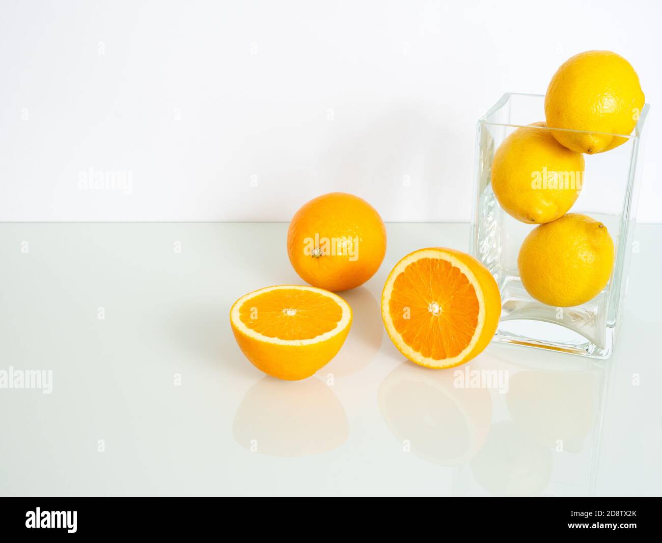 fresh yellow oranges and lemons in a glass vase on a white background