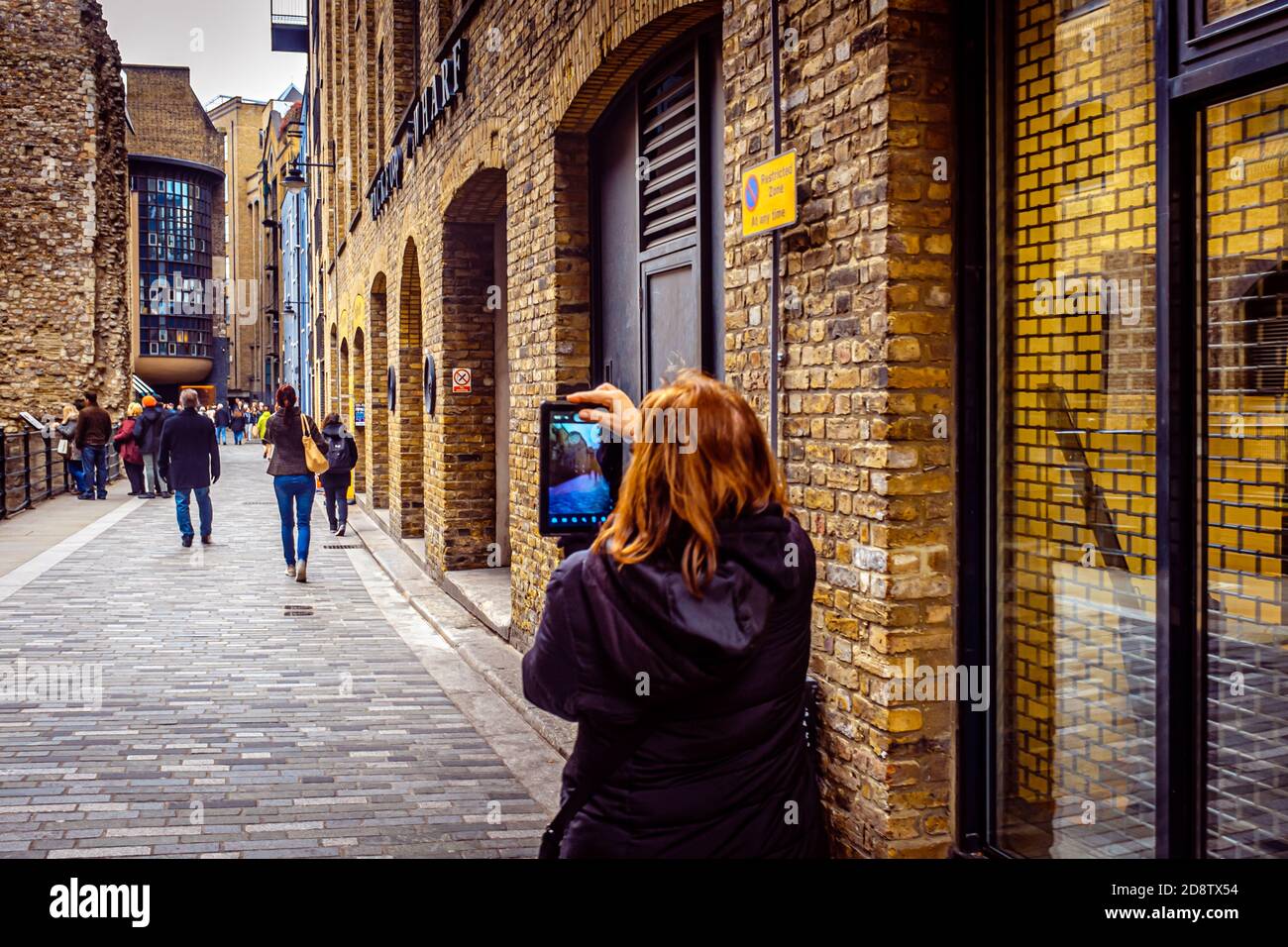 London, UK, December 7, 2013: woman is taking a photo of passersby near Clink Street, Pickfords Wharf Stock Photo