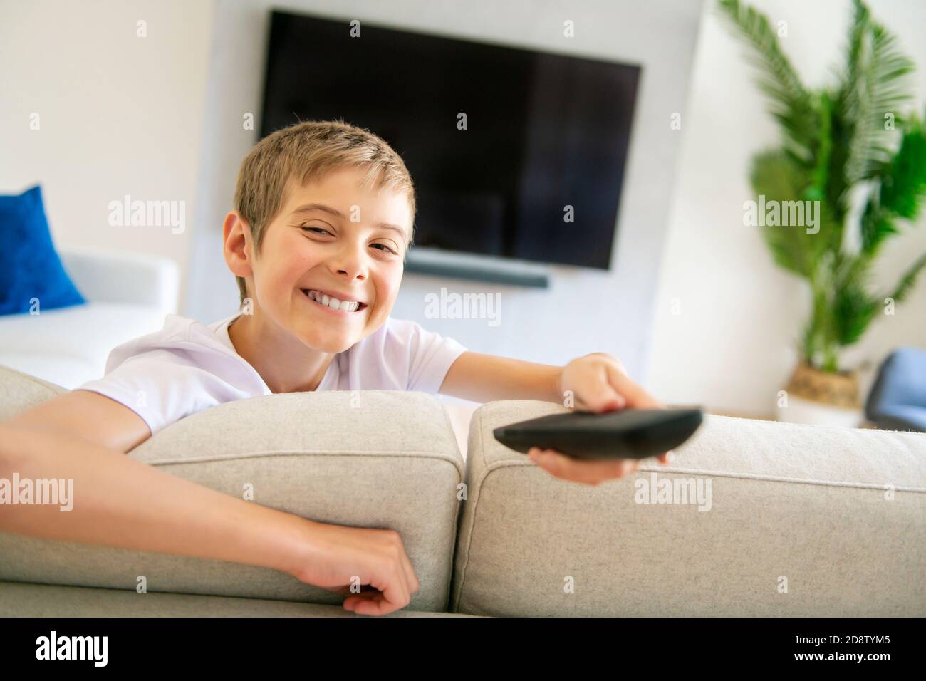 A boy holding remote control and watching TV show Stock Photo