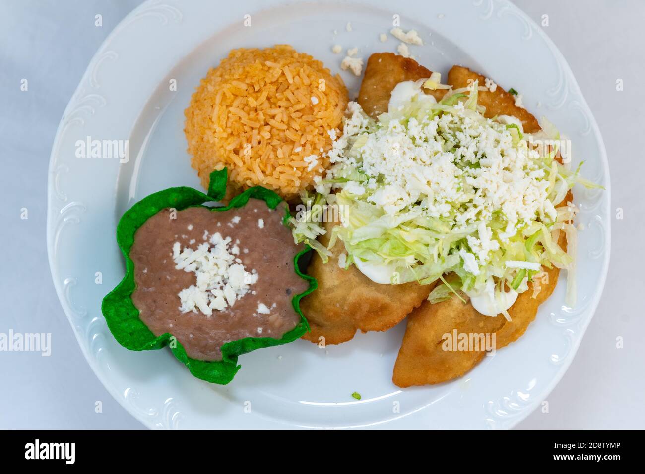 Overhead view of fried Quesadillas served with rice and tortilla chip bowl refried beans looks and tastes appealing. Stock Photo