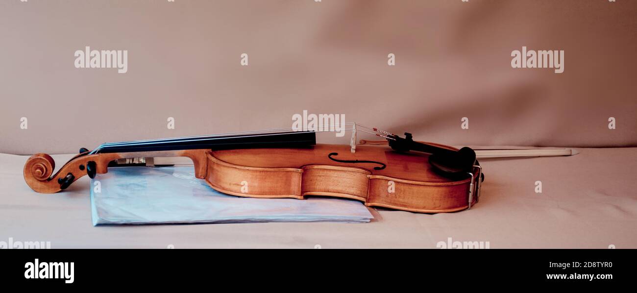 Violin with bow and blue folder for music sheets on table Stock Photo