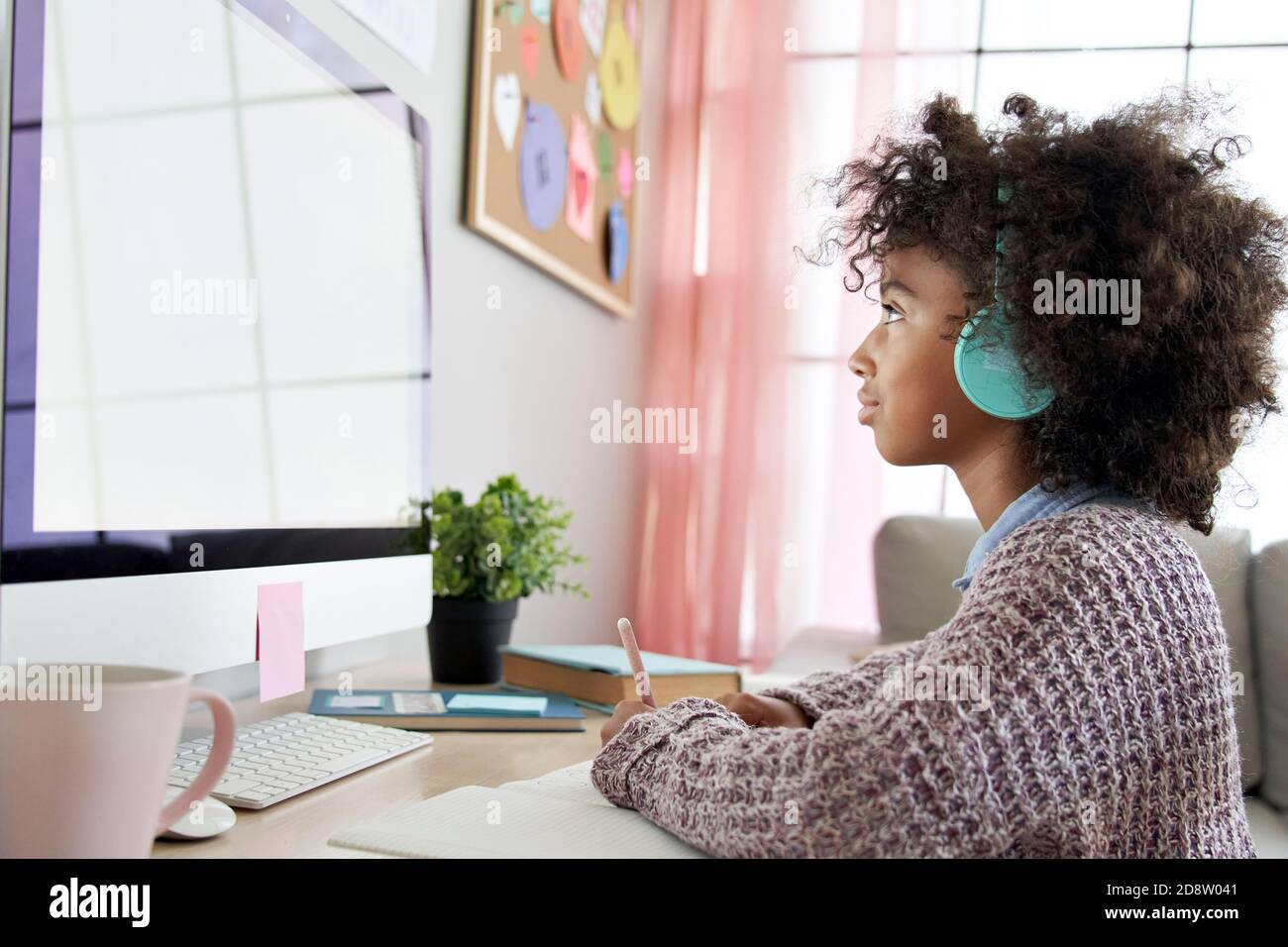 African school child girl wearing headphones virtual online learning at home. Stock Photo
