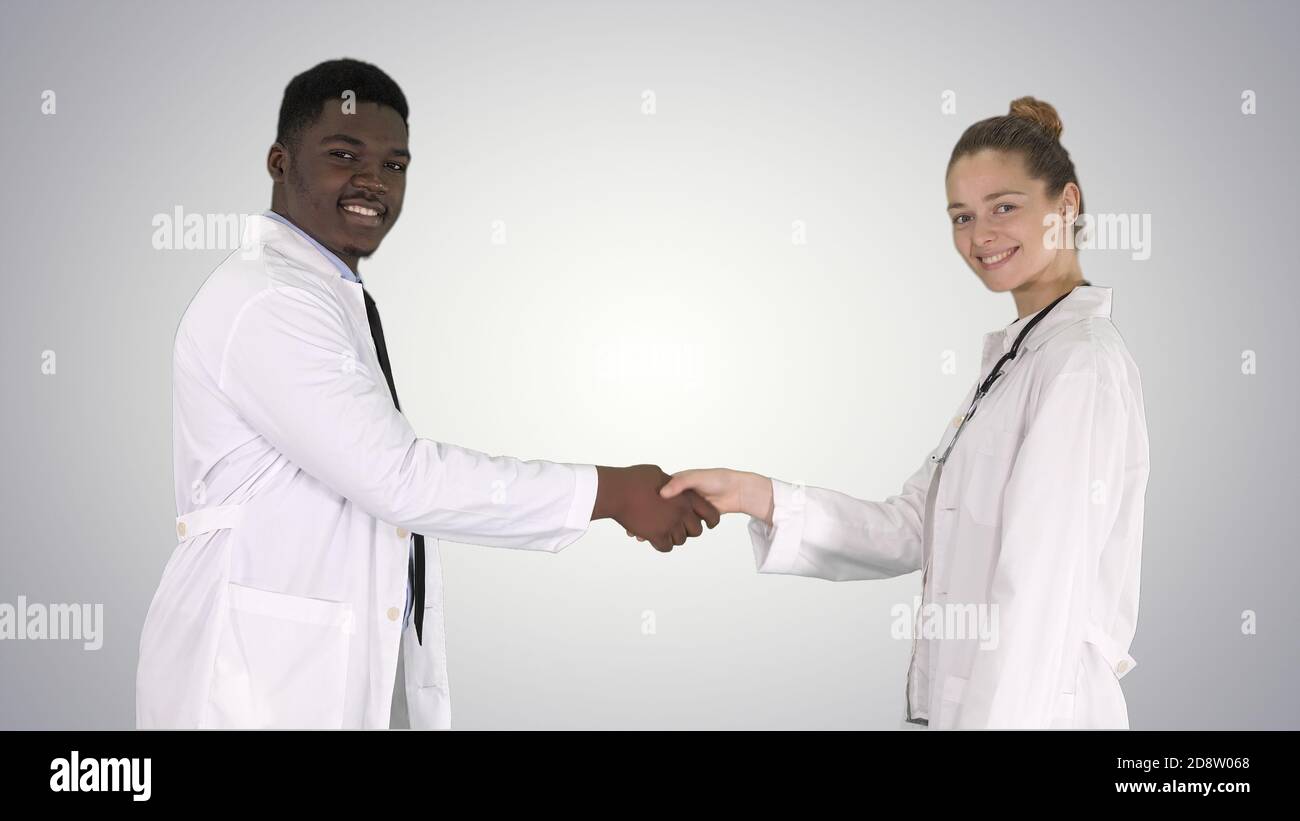 Doctors shaking hands and posing to camera on gradient backgroun Stock Photo