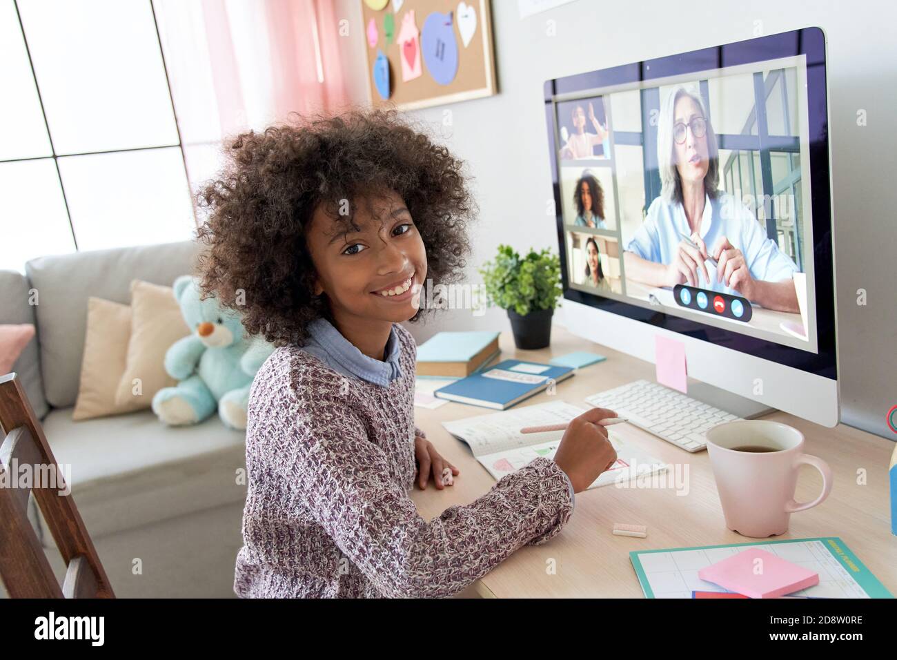 African kid girl looking at camera during online class with teacher, children. Stock Photo