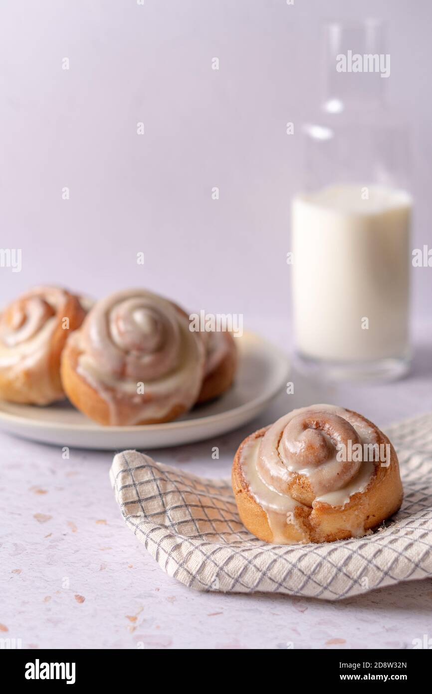 Beautiful white vertical composition of freshly baked cinnamon rolls and a bottle of fresh milk Stock Photo