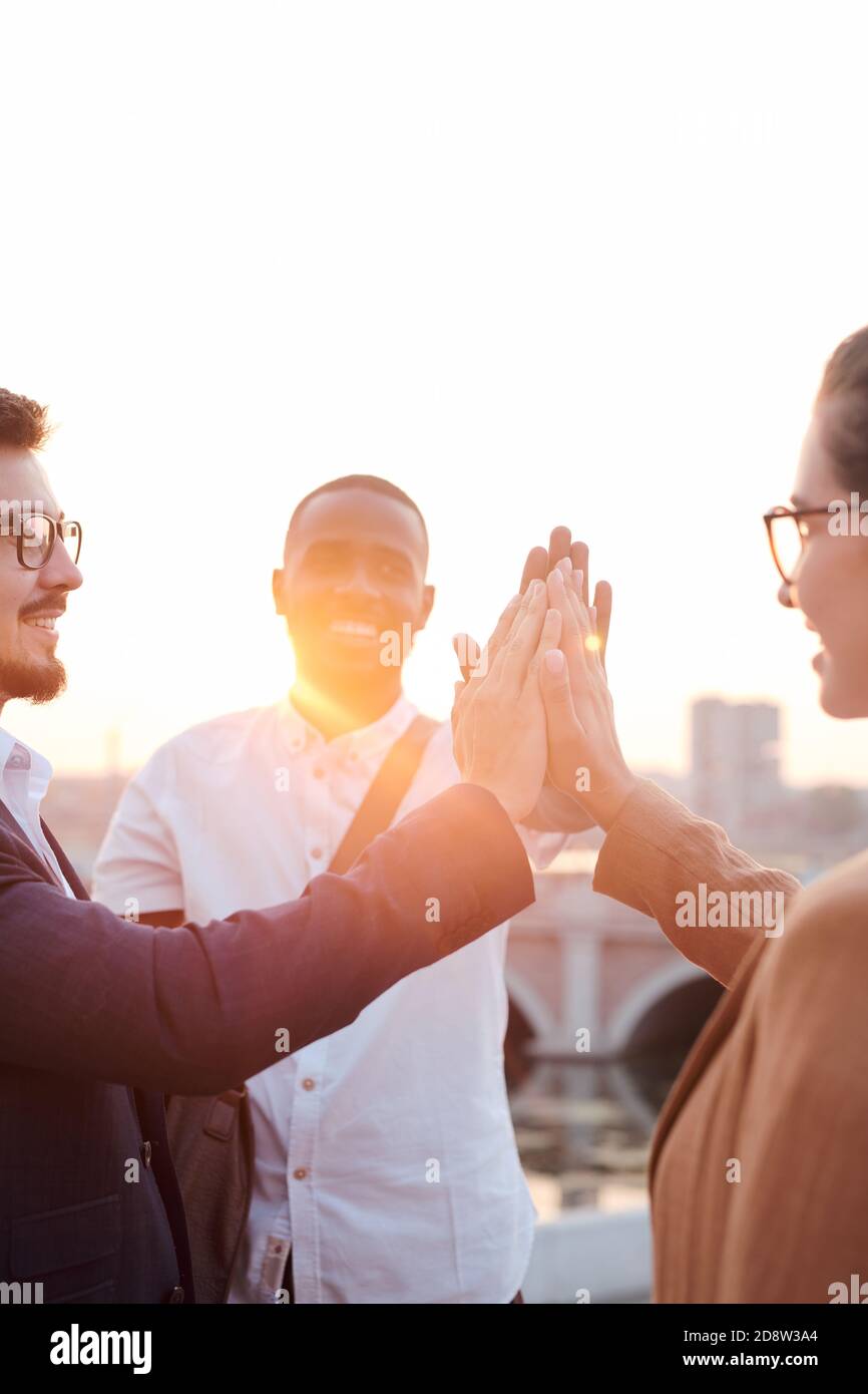 Cheerful colleagues giving each other high five while standing by riverside Stock Photo