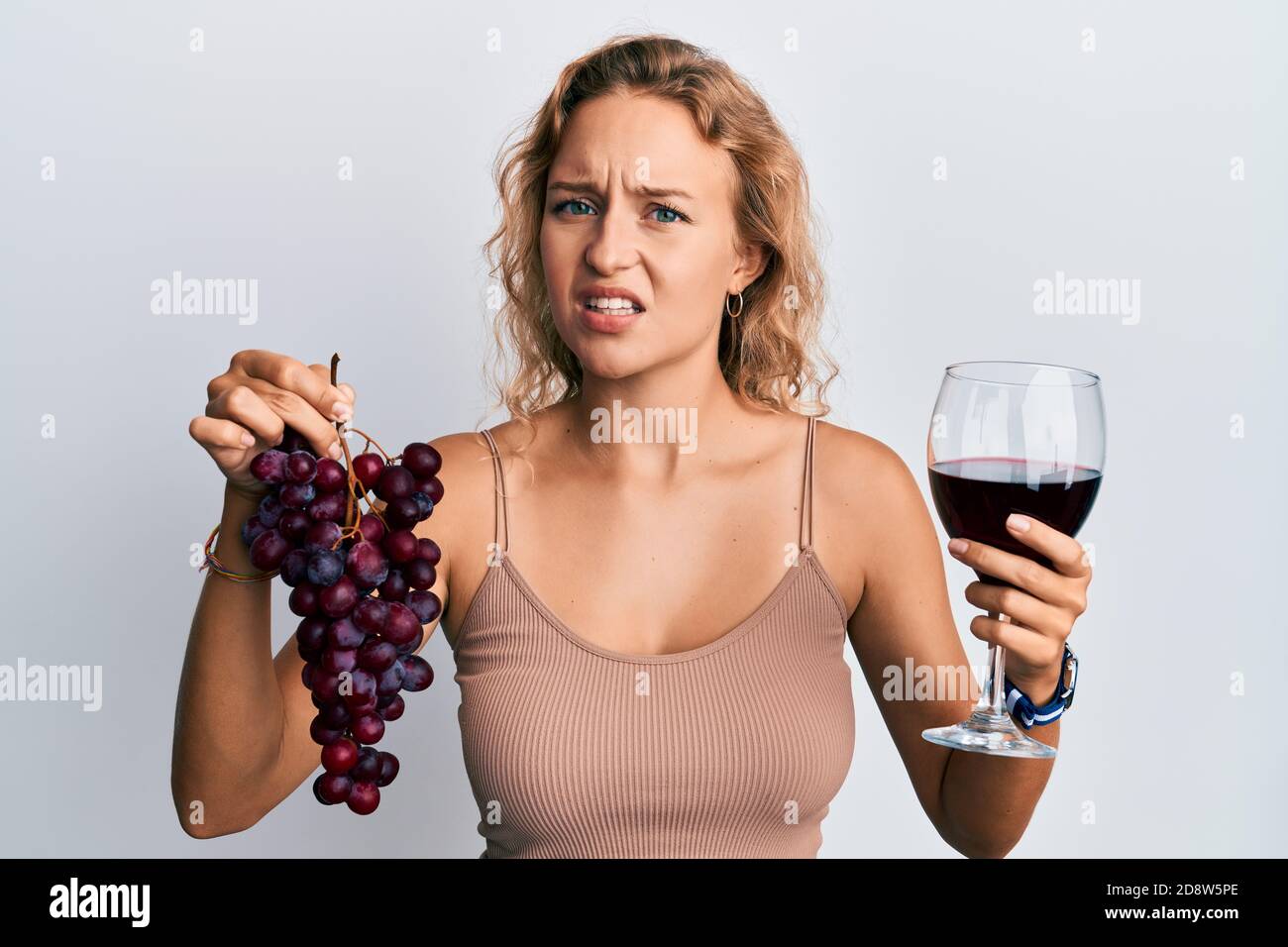 Beautiful caucasian woman holding branch of fresh grapes and red wine ...