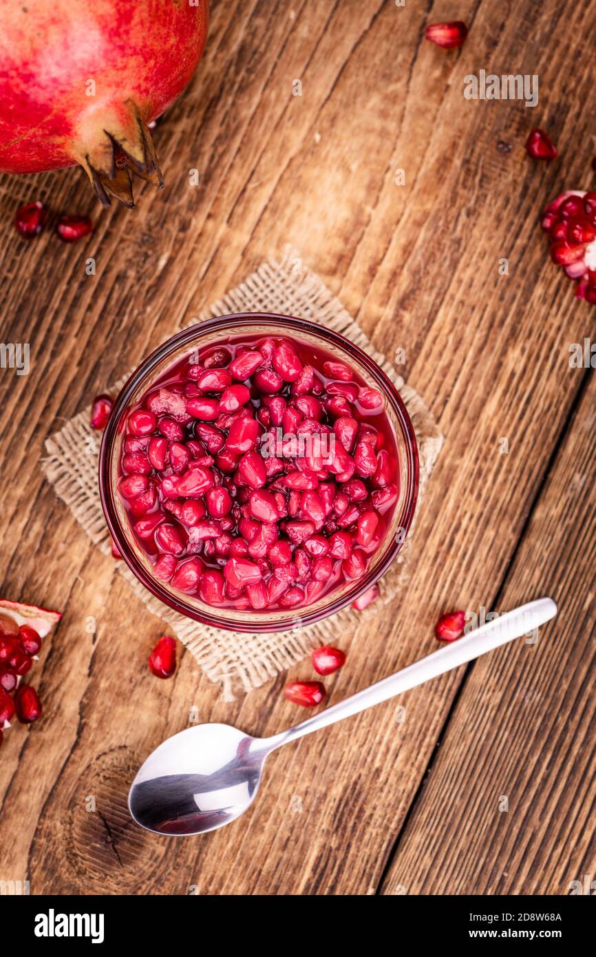 Some preserved Pomegranate seeds on a vintage wooden table (selective focus; close-up shot) Stock Photo