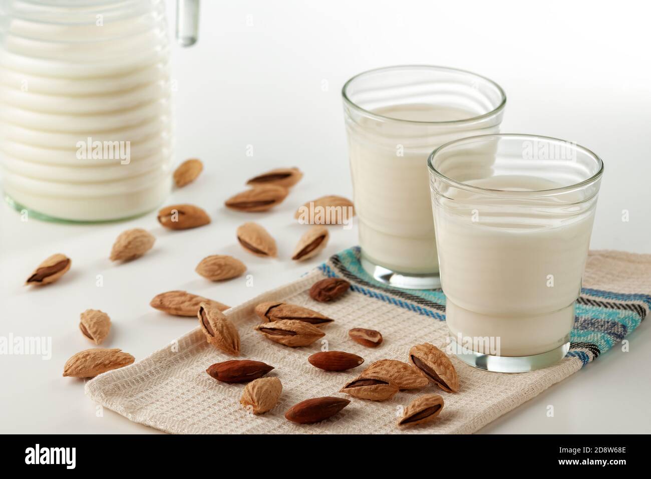 Almond milk in a glass with almonds on a white table Stock Photo