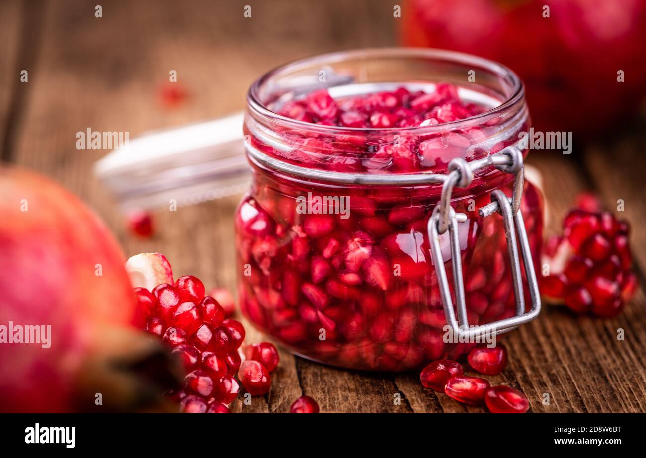 Vintage wooden table with preserved Pomegranate seeds (selective focus; close-up shot) Stock Photo