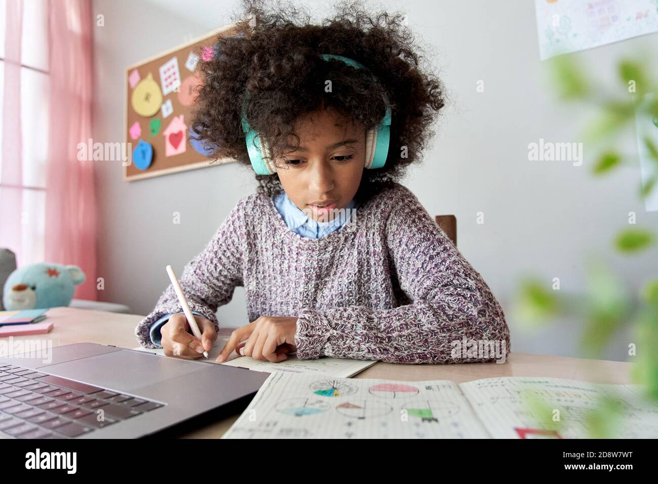 African school child girl wearing headphones online distance learning at home. Stock Photo