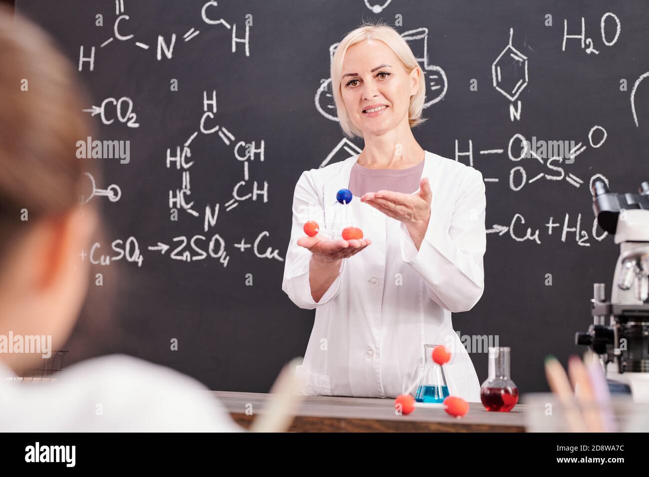 Smiling teacher of chemistry presenting model of molecule of chemical compound Stock Photo