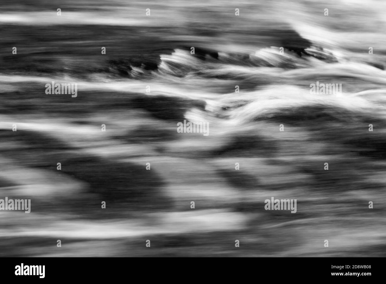 Detail view of flowing water of a small river, high-contrast black and white image, flowing structures, long time exposure Stock Photo