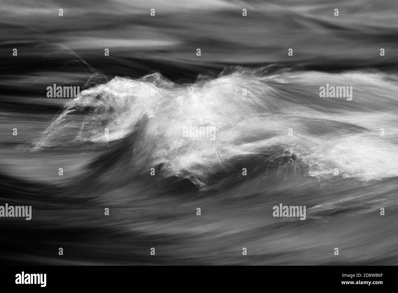 Detail view of flowing water of a small river, high-contrast black and white image, flowing structure, long time exposure, narrow focus zone Stock Photo