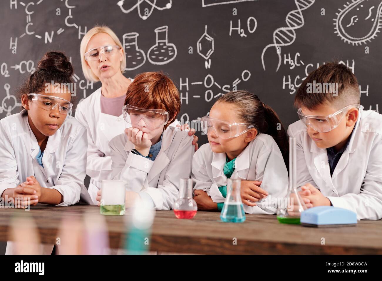 Schoolkids watching different reactions in glass tubes with chemical