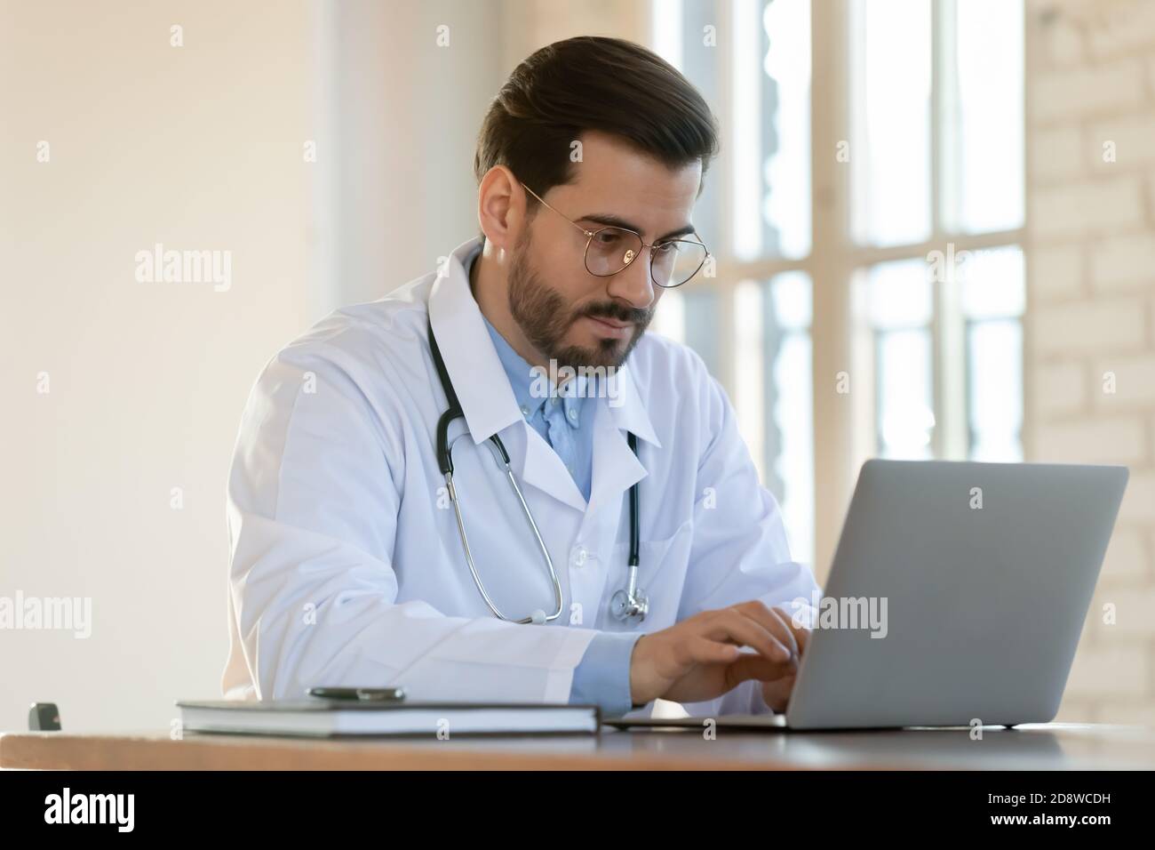 Inspired millennial doctor using computer to read medical literature online Stock Photo