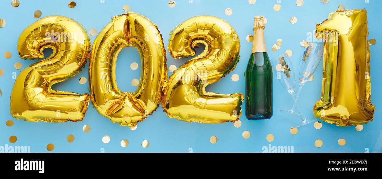 2021 golden balloon text on blue background bottle of champagne and glasses with confetti. Happy New year eve invitation with Christmas gold foil Stock Photo