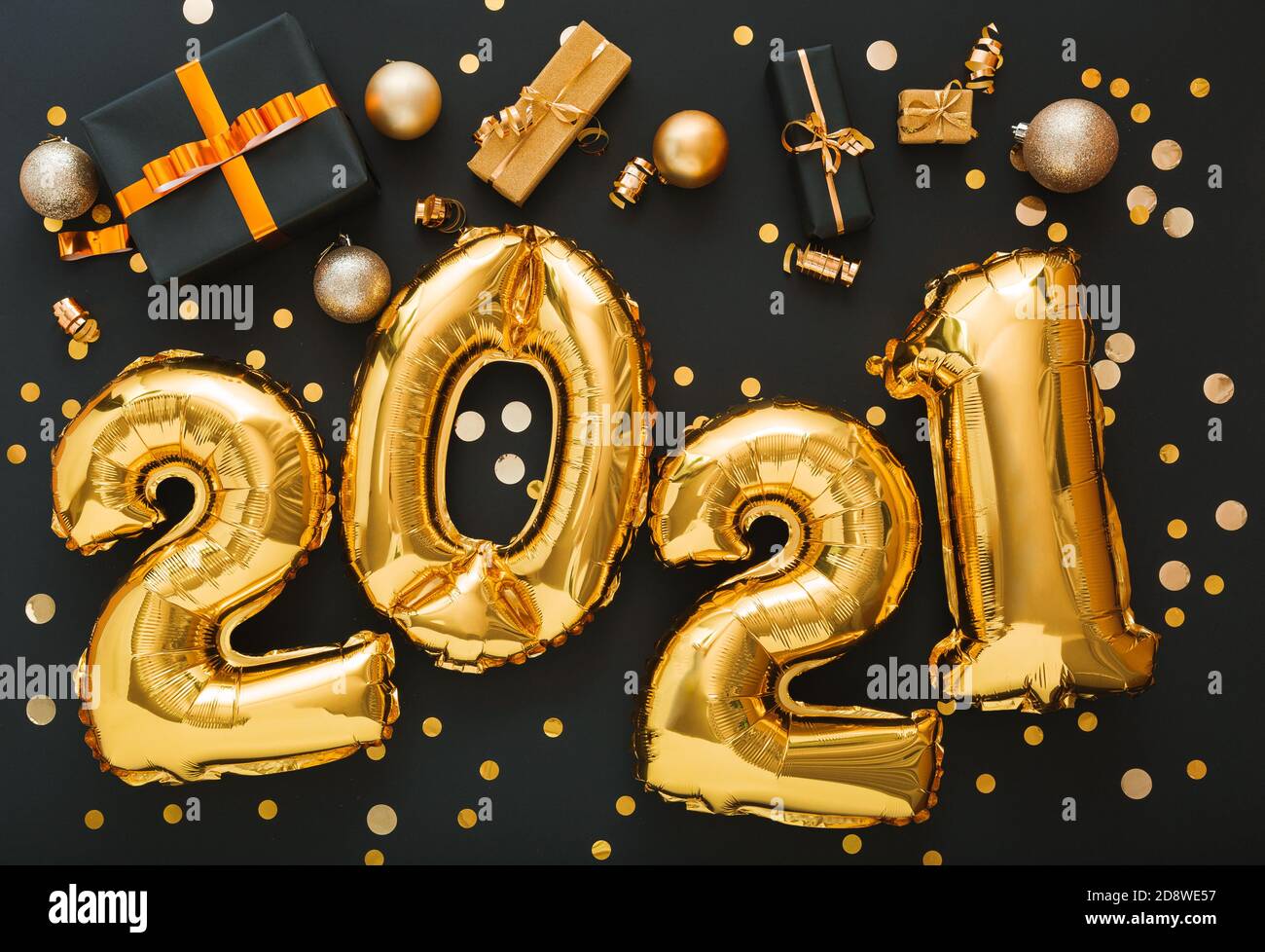 2021 balloon gold text on black background with golden confetti, Christmas gift boxes, gold balls, festive decor. Happy New year eve invitation with Stock Photo