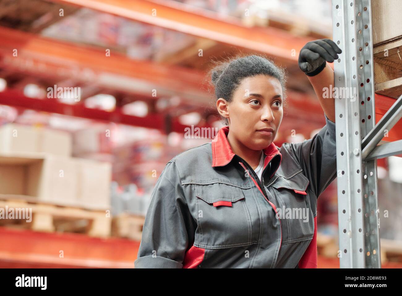 Middle aged mixed-race female worker in gloves and grey uniform having rest Stock Photo