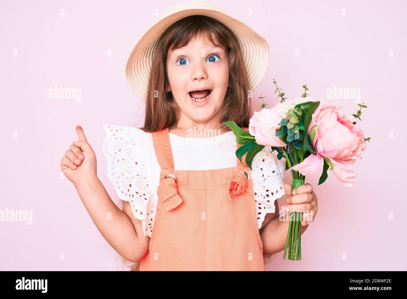 Little caucasian kid girl with long hair holding flower wearing spring ...