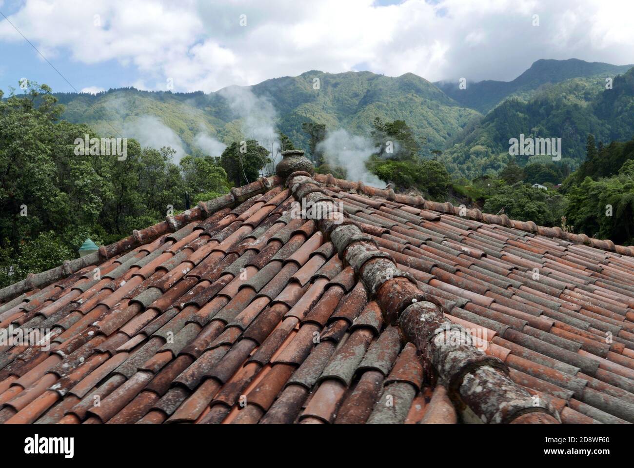 Steam from hot springs rising over tiled Portuguese style roofs in Furnos  on the island of San Miguel  in the Azores. Stock Photo