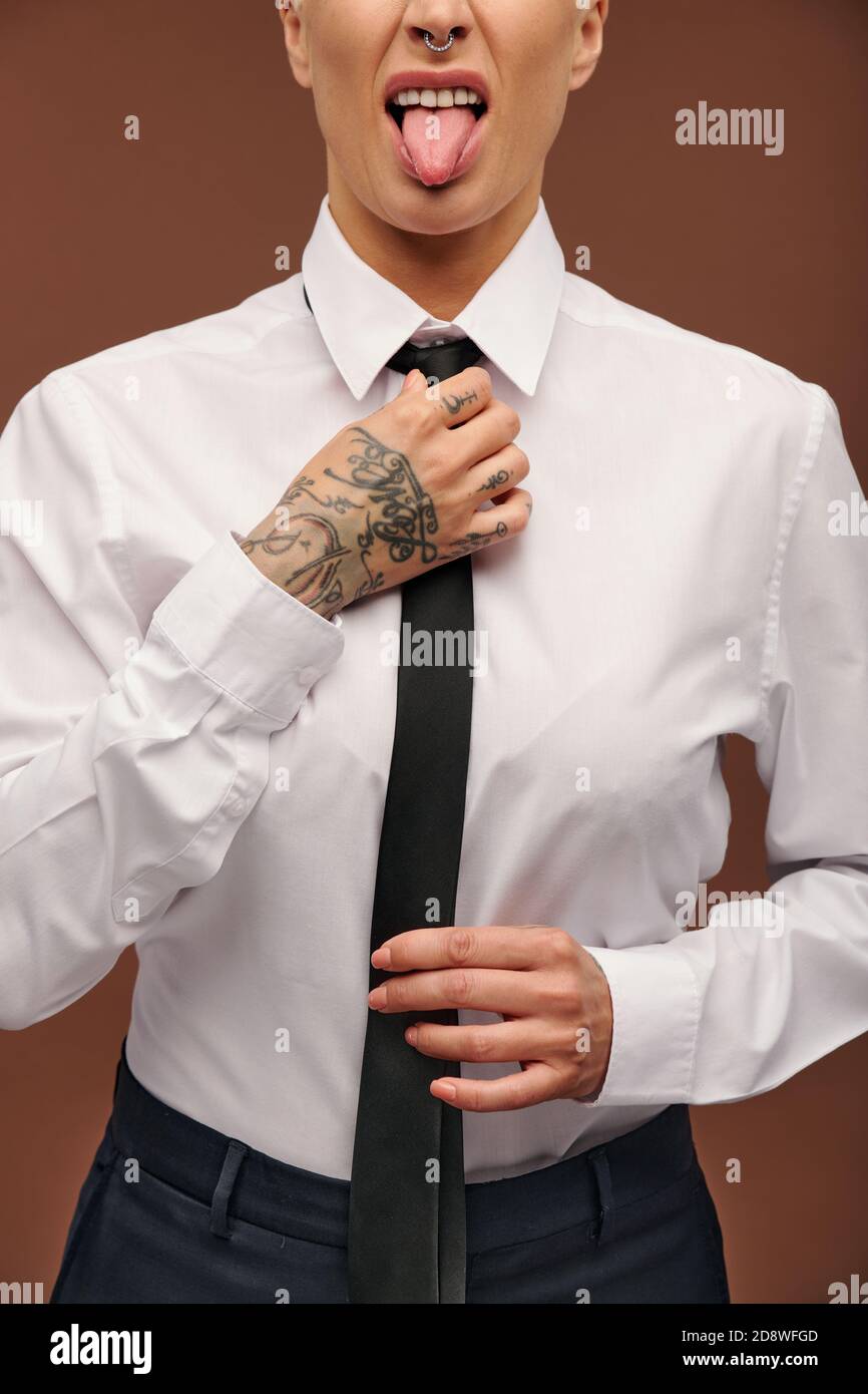 Manlike middle aged businesswoman showing tongue and putting on black necktie Stock Photo