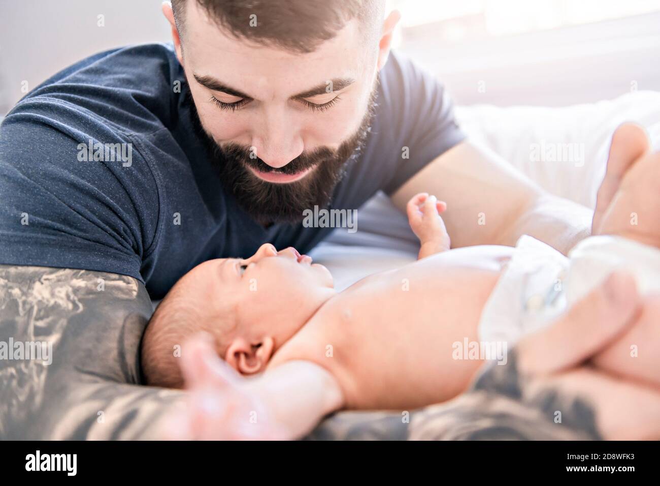 father lay on bed with his newborn baby daughter Stock Photo Alamy