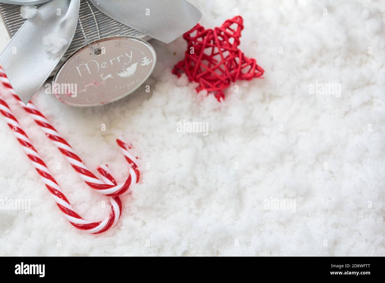 Top view of gift box, candy canes and red star on snowy background with ...