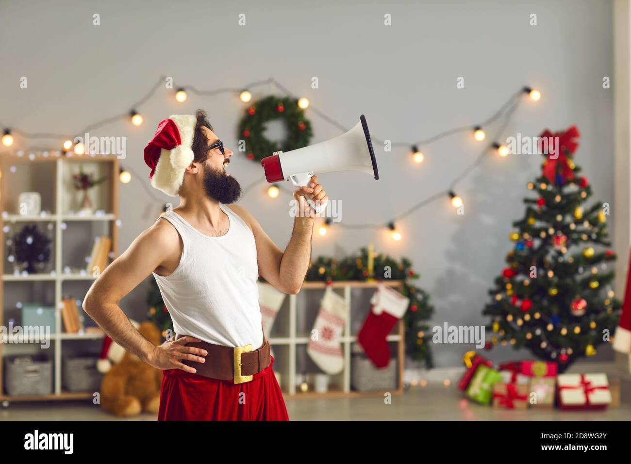 Man in Santa cap and funny holiday costume standing and shouting in speaker Stock Photo