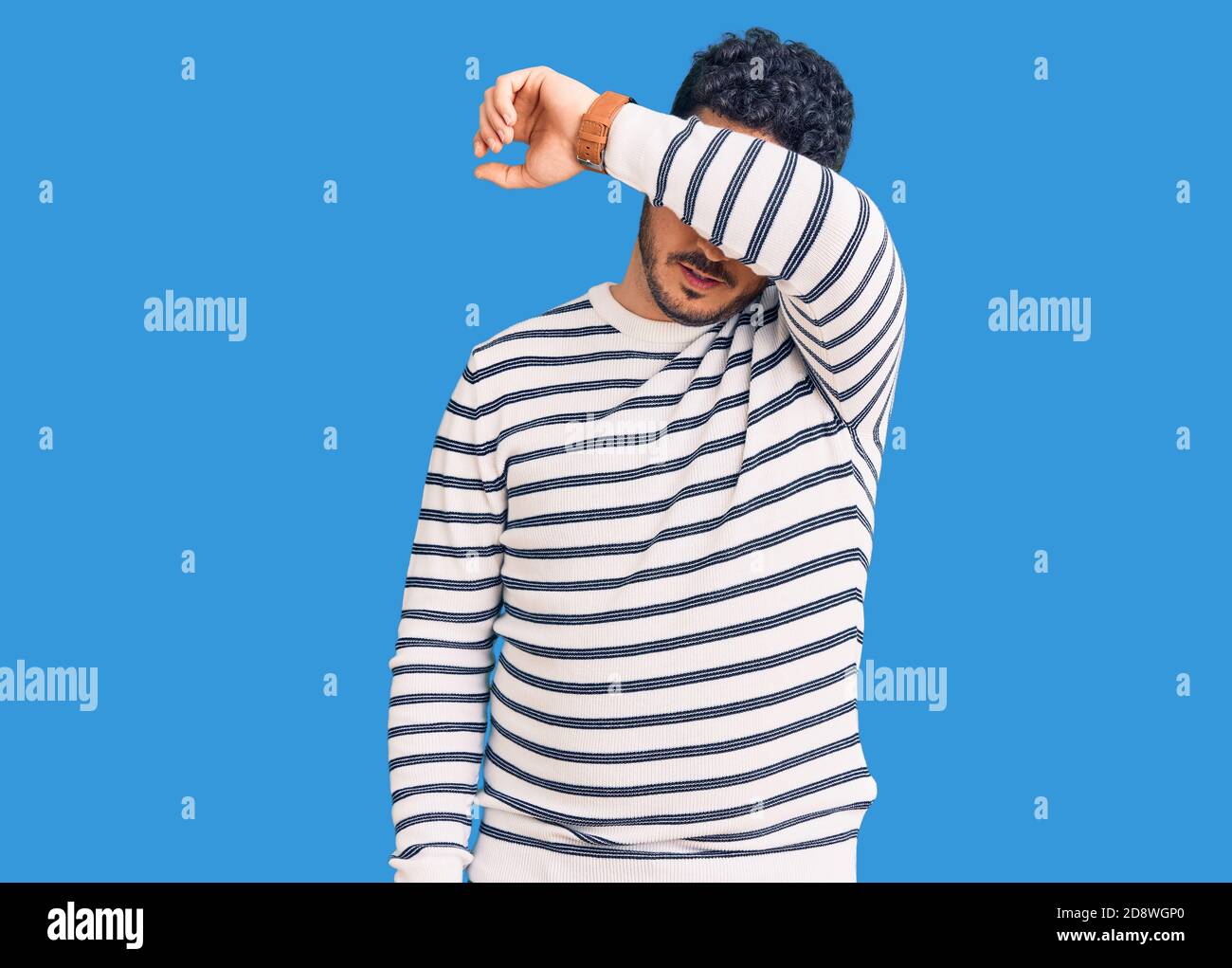 Young hispanic man wearing casual clothes covering eyes with arm ...
