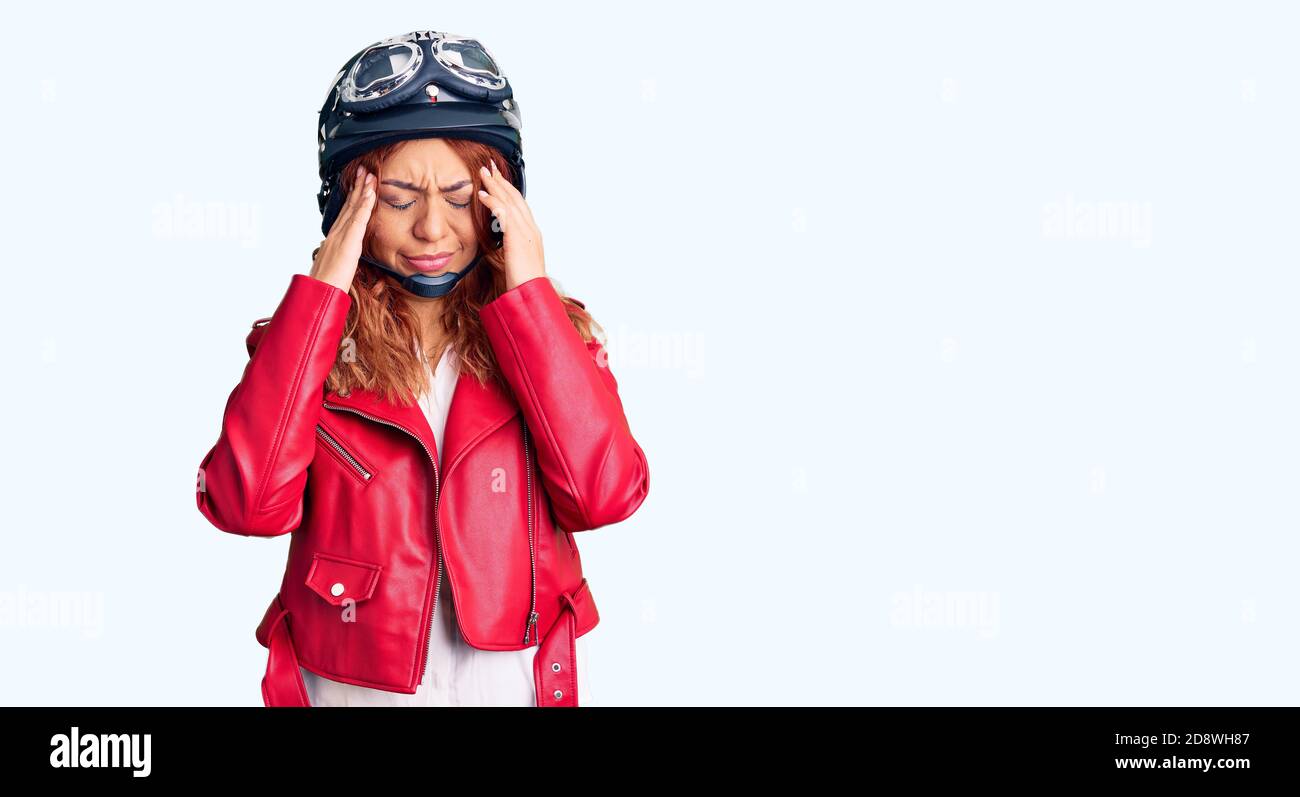 Young latin woman wearing leather jacket holding motorcycle helmet