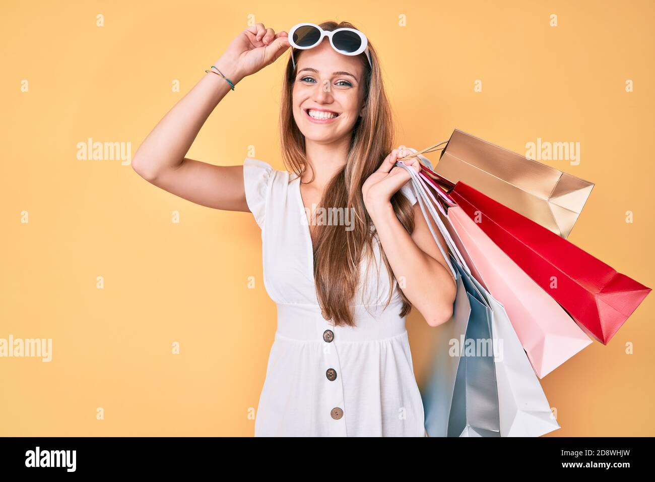 Young blonde girl holding shopping bags smiling with a happy and cool ...