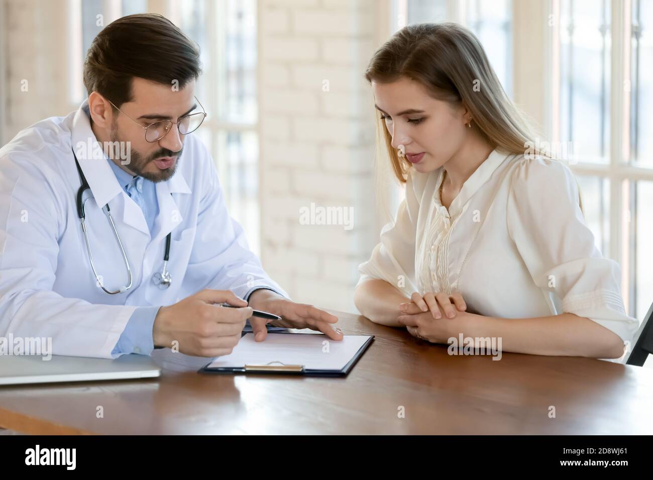 Capable qualified male doctor prescribing treatment to young female patient Stock Photo