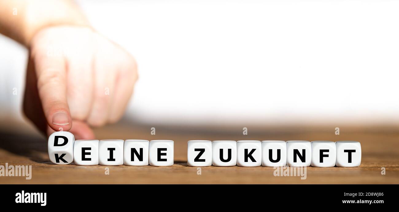 Hand turns dice and changes the German expression 'keine Zukunft' (no future) to 'Deine Zukunft' (your future). Stock Photo