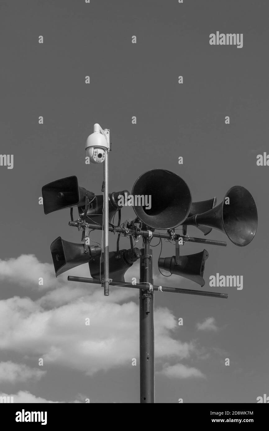 Tannoy or loudspeaker system and surveillance camera against a dark sky - monochrome.  Dystopian suggestions. Stock Photo