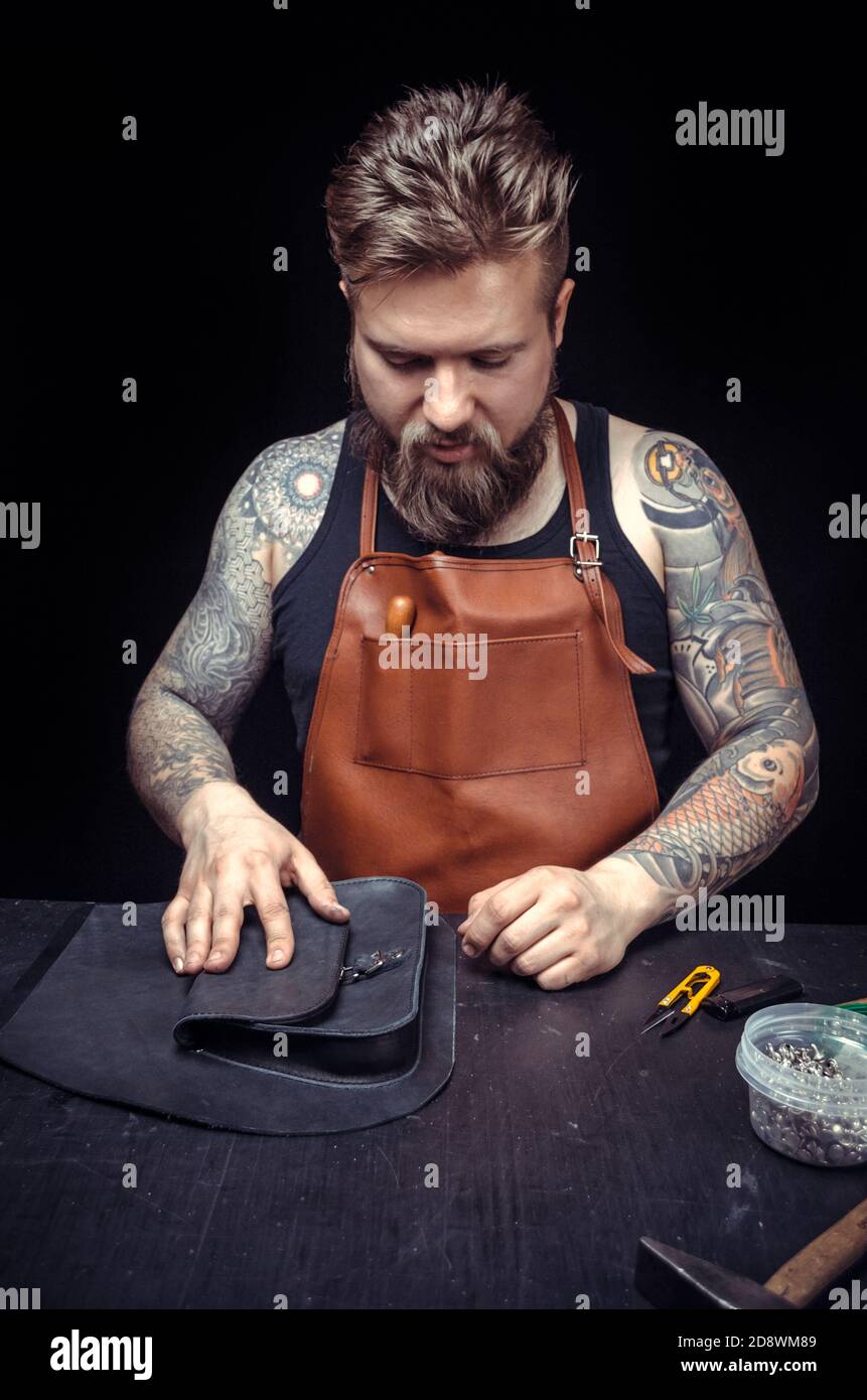 Skinner demostrating leather cutting process in leather shop Stock Photo
