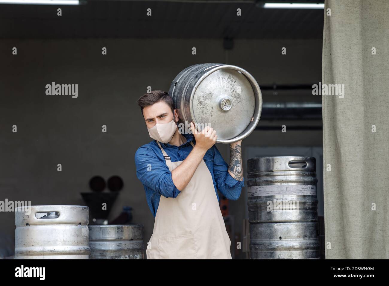 Young man working at warehouse in brewery or employee with keg Stock Photo