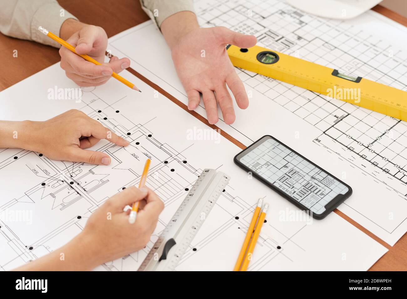 Hands of two young engineers with pencils over sketches of new construction Stock Photo