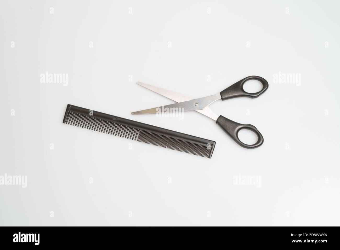stainless steel scissors with black handle lie and comb on a light table Stock Photo