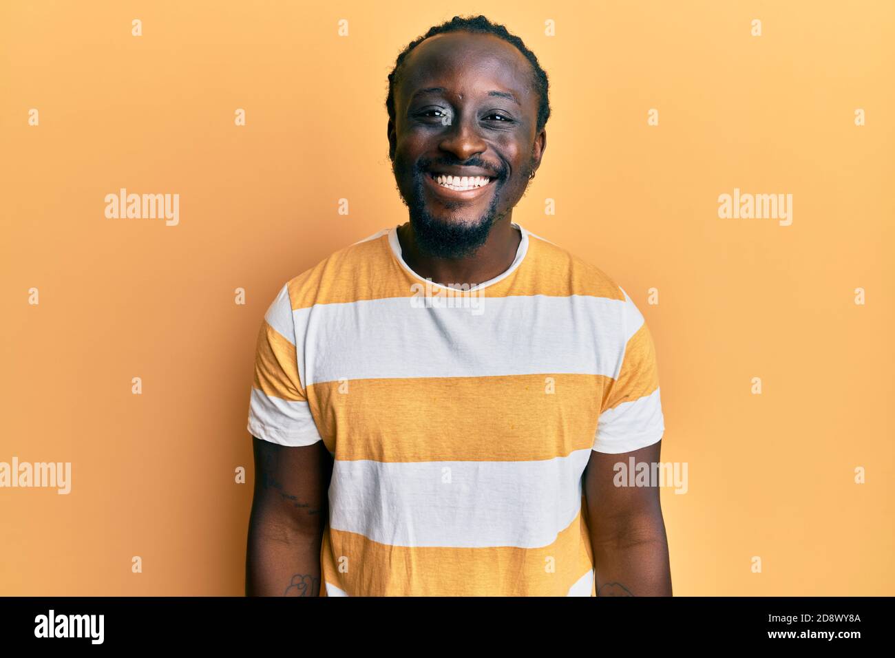Handsome young black man wearing casual yellow tshirt looking positive ...