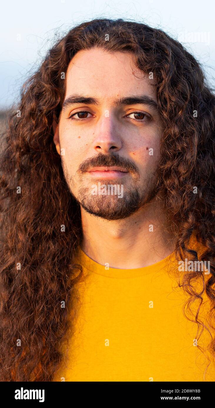 Vertical shot of a young man with long curly hair Stock Photo