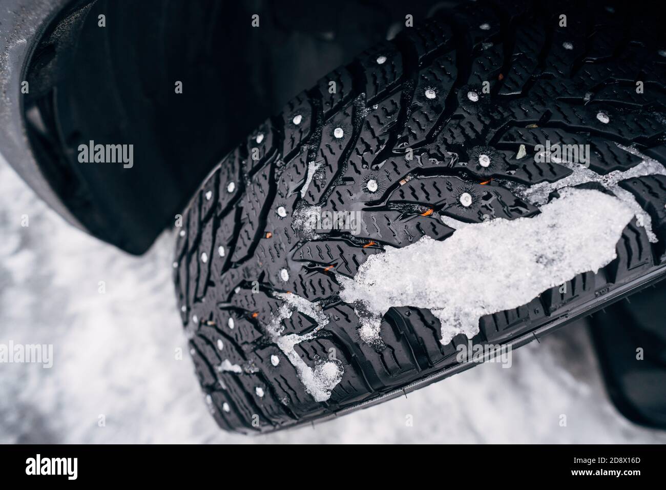Winter tire. Car on snow road. Tires on snowy highway detail. Stock Photo