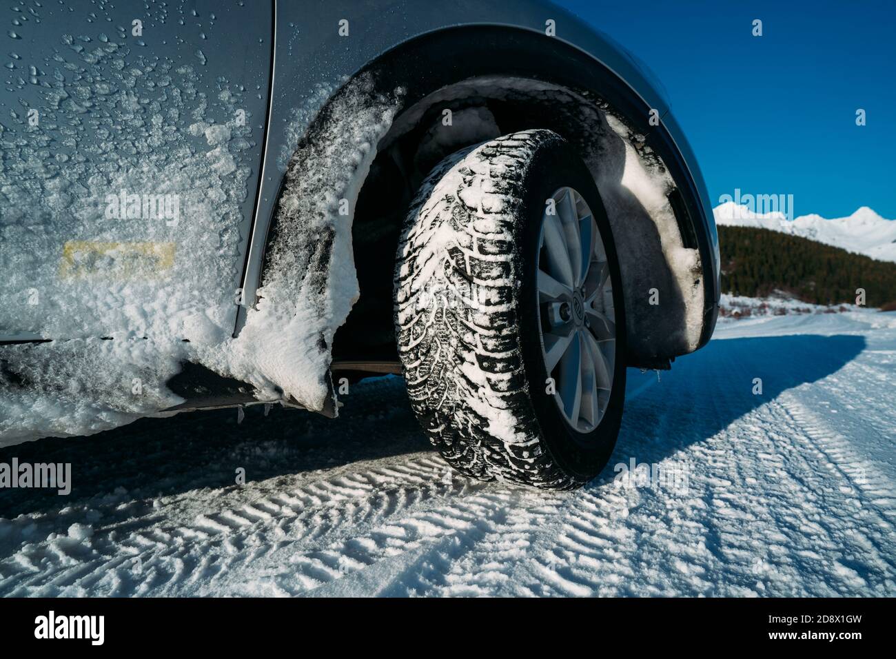 Winter tire. Car on snow road. Tires on snowy highway detail. Stock Photo