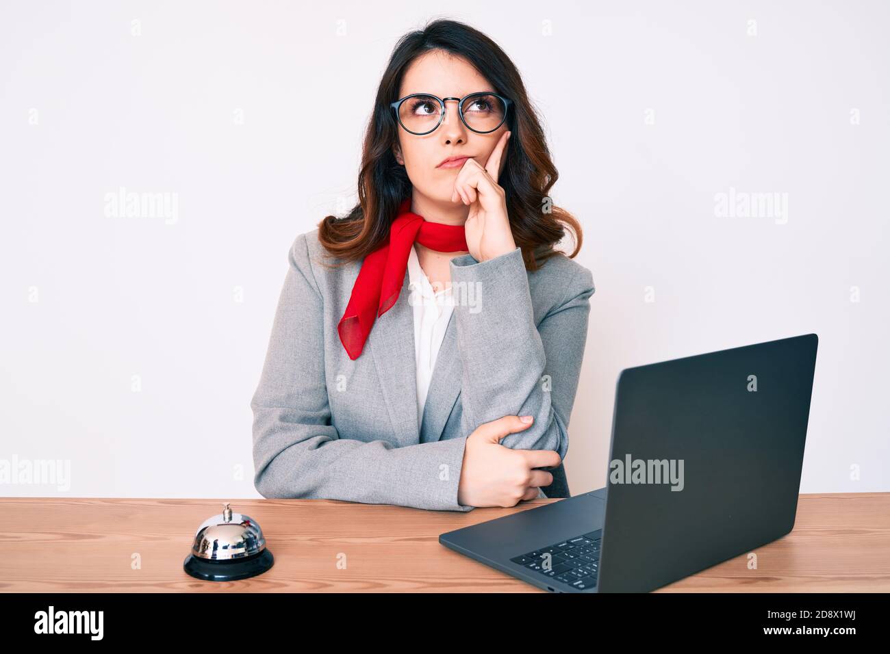 Young beautiful brunette woman working at hotel reception using laptop ...