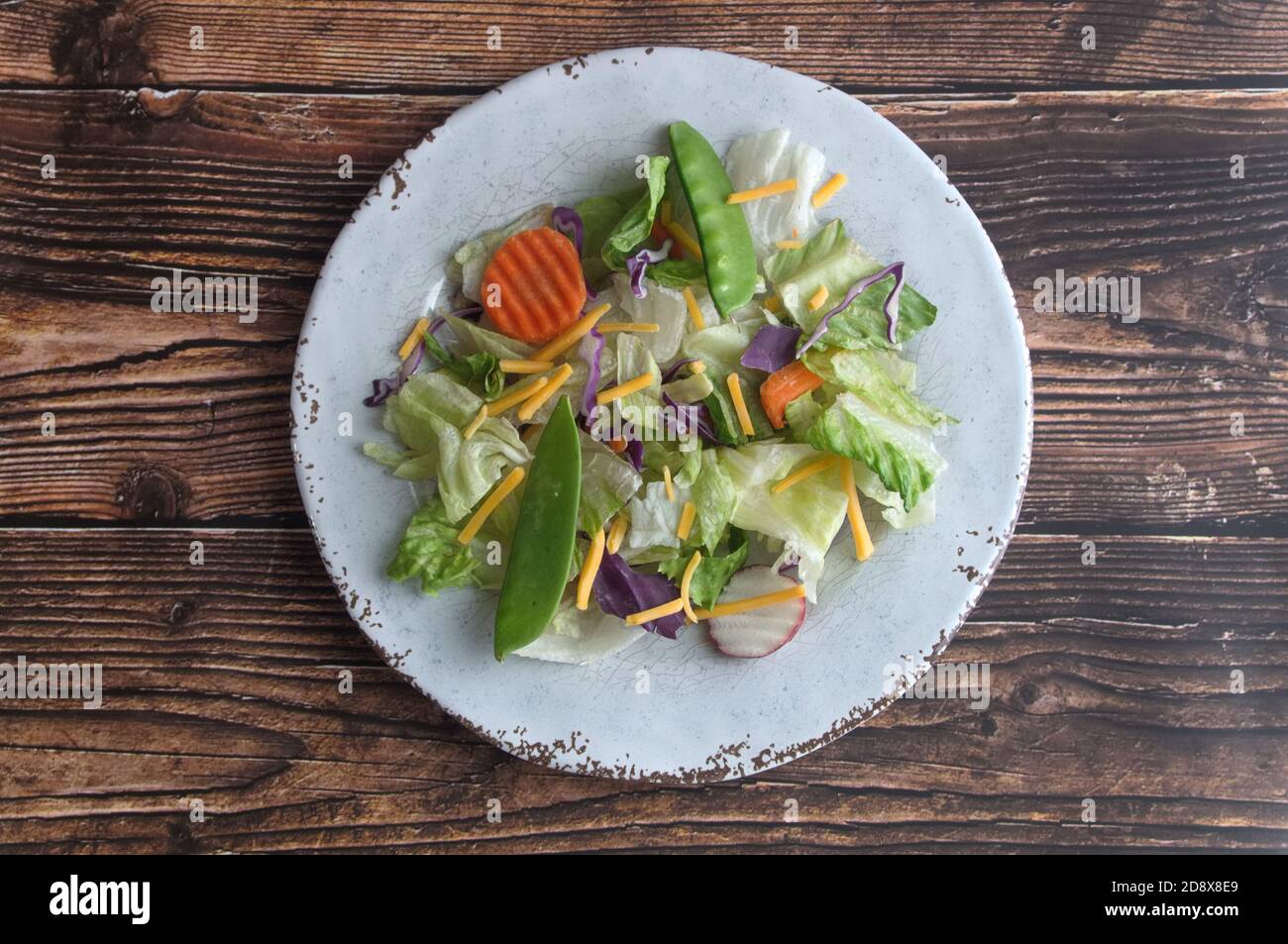 Mixed vegetable salad on a white plate centered on a wooden background Stock Photo